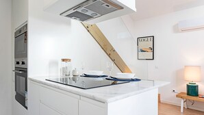 Et moderne køkken med en central ø, indbygget ovn og et loft med træbjælker.