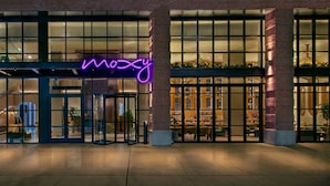 A modern building with large glass windows and a neon sign. - Moxy Brooklyn Williamsburg (Brooklyn)