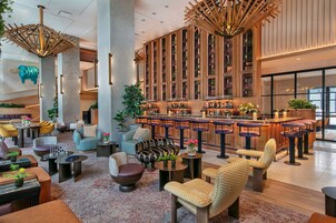A modern bar area with high stools and a bar counter, surrounded by seating with round tables and chairs.