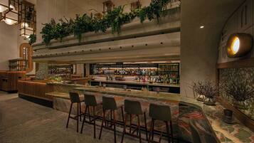 A bar area with a marble countertop, bar stools, and a variety of bottles and glasses.