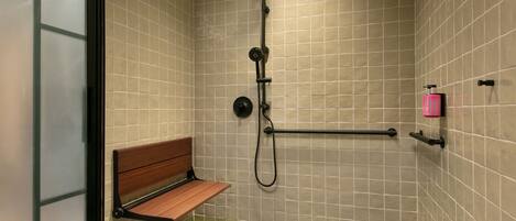 A shower with a bench, a handheld showerhead, and a handheld massager.