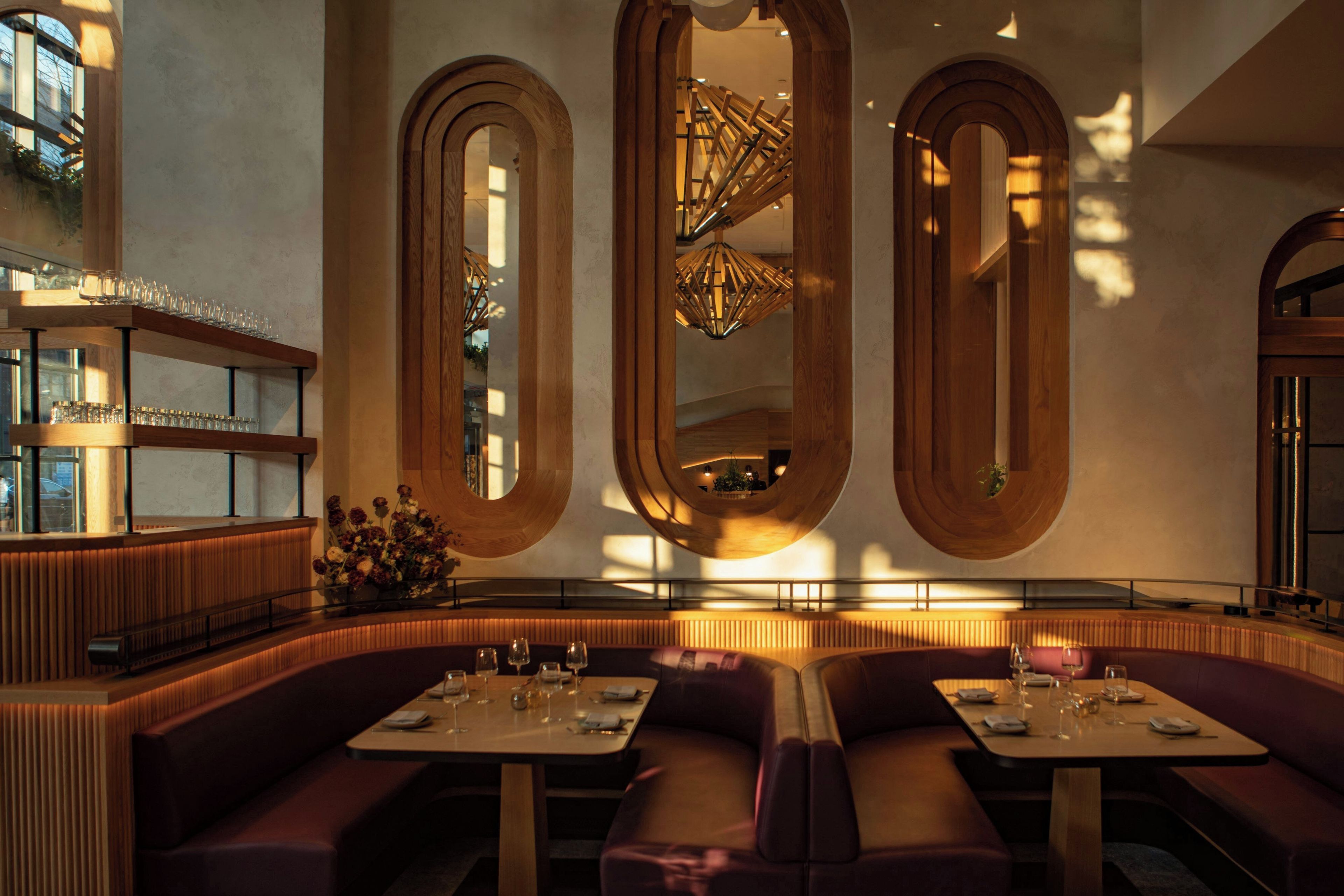 Ein Restaurantinneres mit modernem Design, mit Holzakzenten und einem zentralen Kronleuchter.