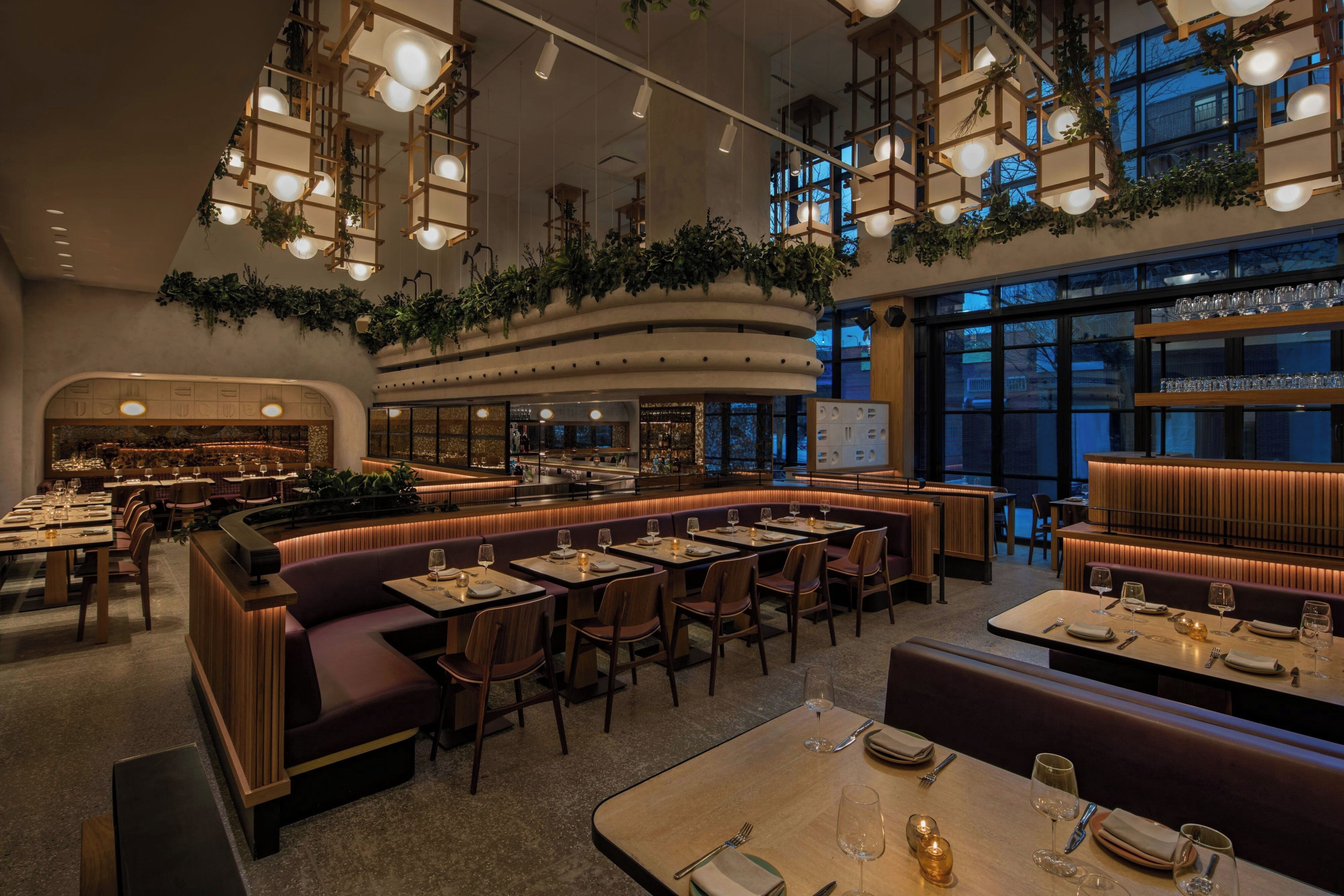 Interior de restaurante con barra, disposición de mesas y amplios ventanales.