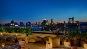 A rooftop bar with seating and tables, overlooking a city skyline at dusk. - Moxy Brooklyn Williamsburg (Brooklyn)