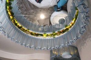 Un atrio circular con techo de cristal, una lámpara central y una guirnalda decorativa.