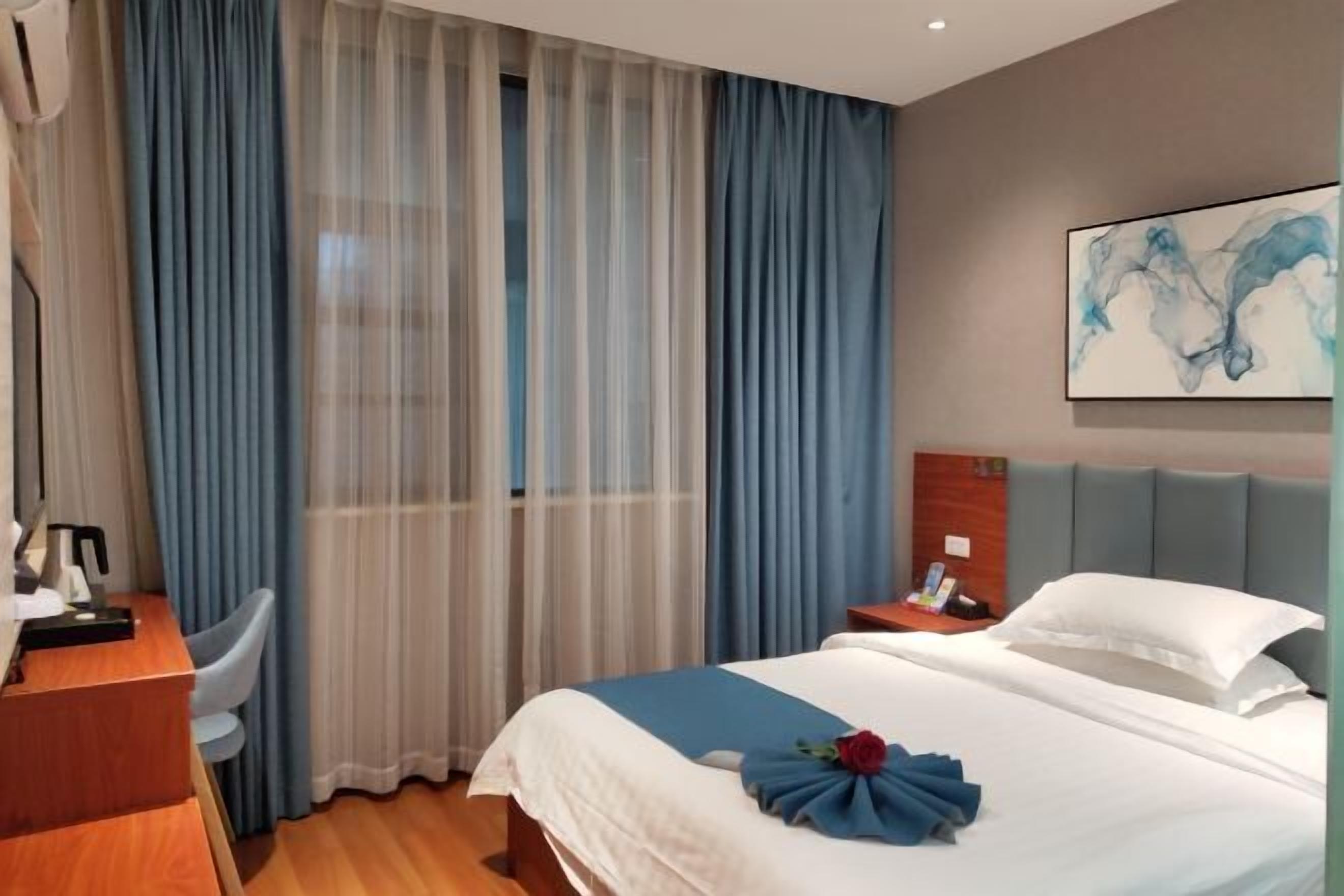 A hotel room with a bed, a desk, a chair, and a nightstand.