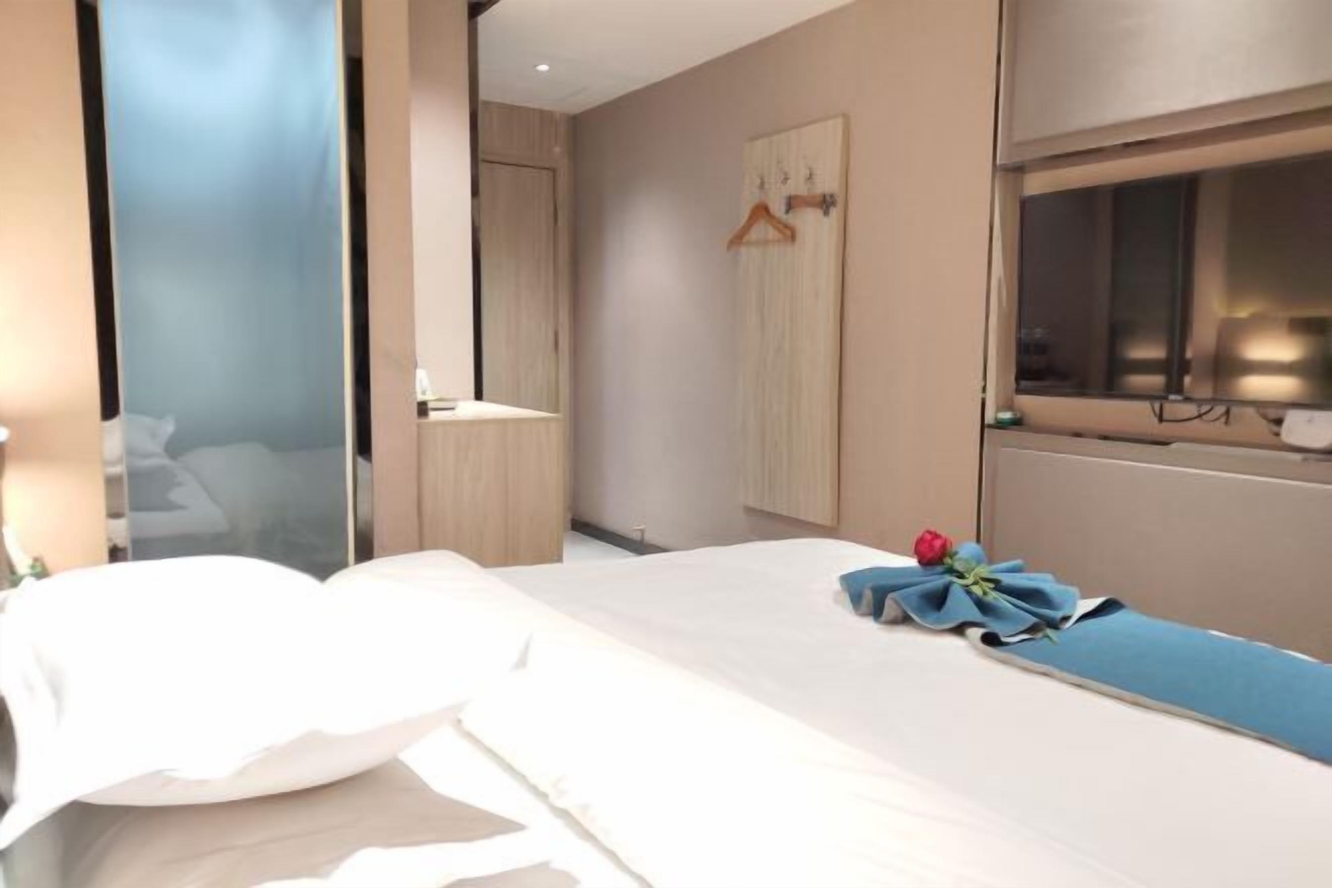 A hotel room with a bed, a window, a mirror, and a wardrobe.
