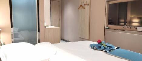 A hotel room with a bed, a window, a mirror, and a wardrobe.