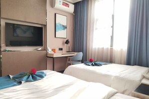 Habitación de hotel con dos camas, un escritorio, un televisor y una ventana con cortinas.