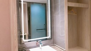 Ein Badezimmer mit großem Spiegel, Waschbecken und Duschbereich.