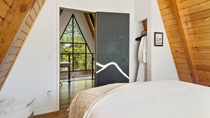 Une chambre avec un grand lit, un plafond en bois et une vue sur l’extérieur par une fenêtre.