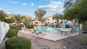 A pool area with lounge chairs and a small garden. - Cozy Cowboy Condo (Paradise Valley)