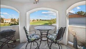 A covered patio with a table and two chairs, a ceiling fan, and a view of a golf course. - Cozy Cowboy Condo (Paradise Valley)