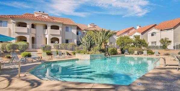 Enjoy a refreshing dip in the pool surrounded by lounge chairs and a palm tree.