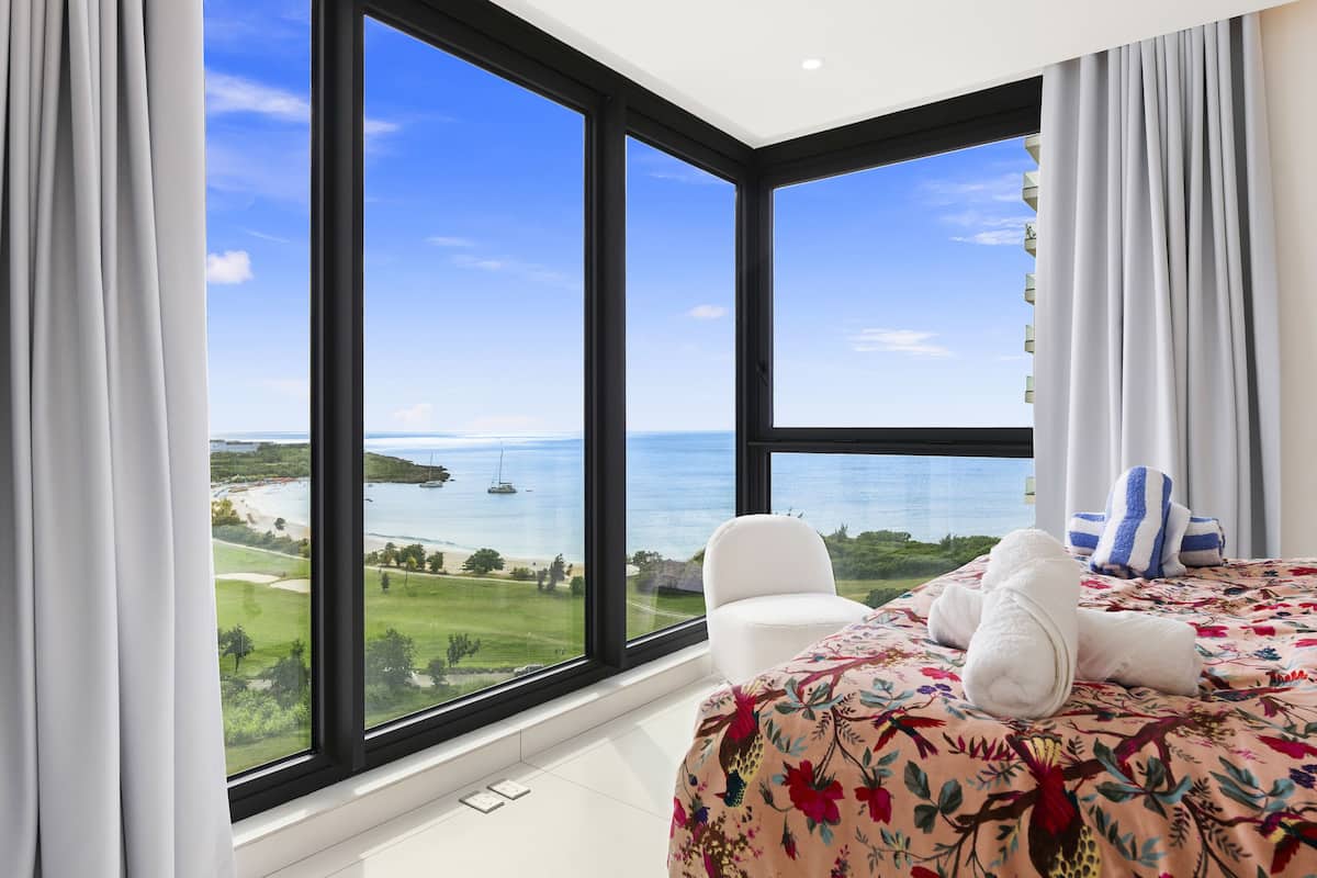 Une chambre d’hôtel dotée d’une grande fenêtre donnant sur la mer et un terrain de golf.