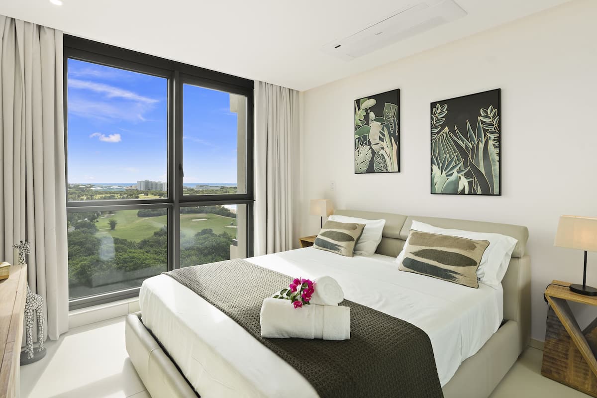 Une chambre moderne avec un grand lit, une vue sur un terrain de golf et deux œuvres d’art murales.