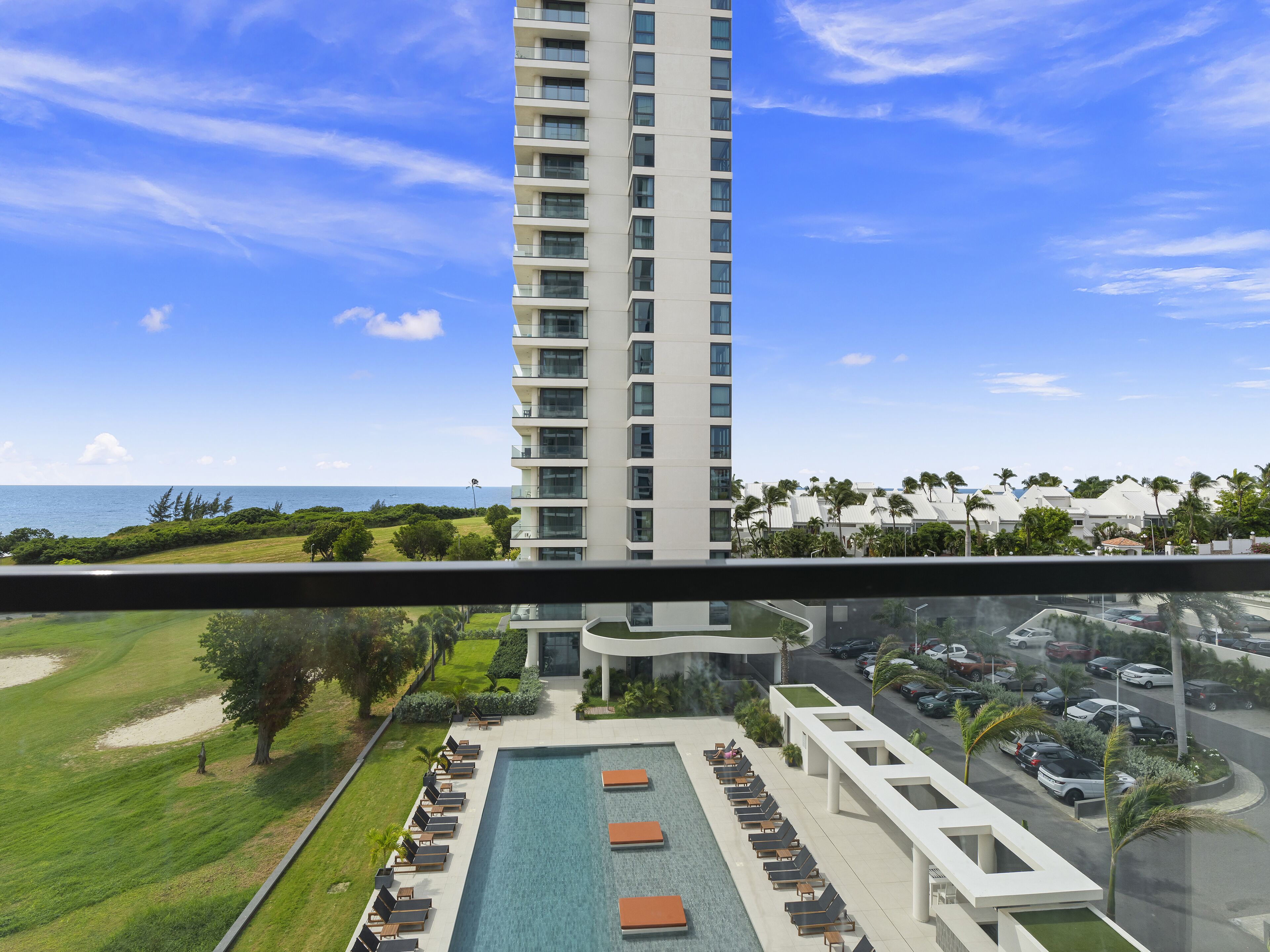 A high-rise hotel with a pool area, outdoor seating, and a view of the ocean.