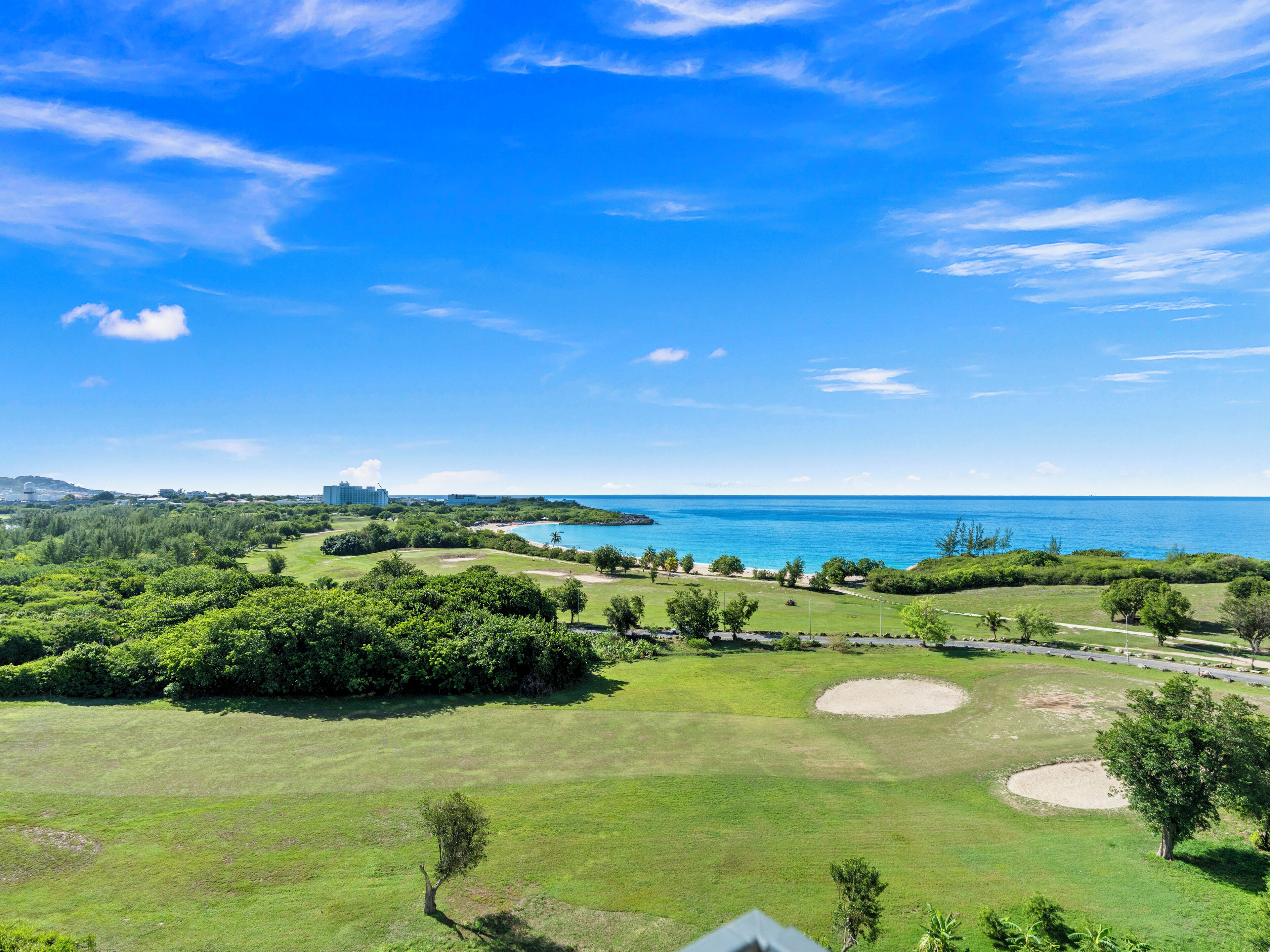 A golf course with a view of the ocean and distant buildings.