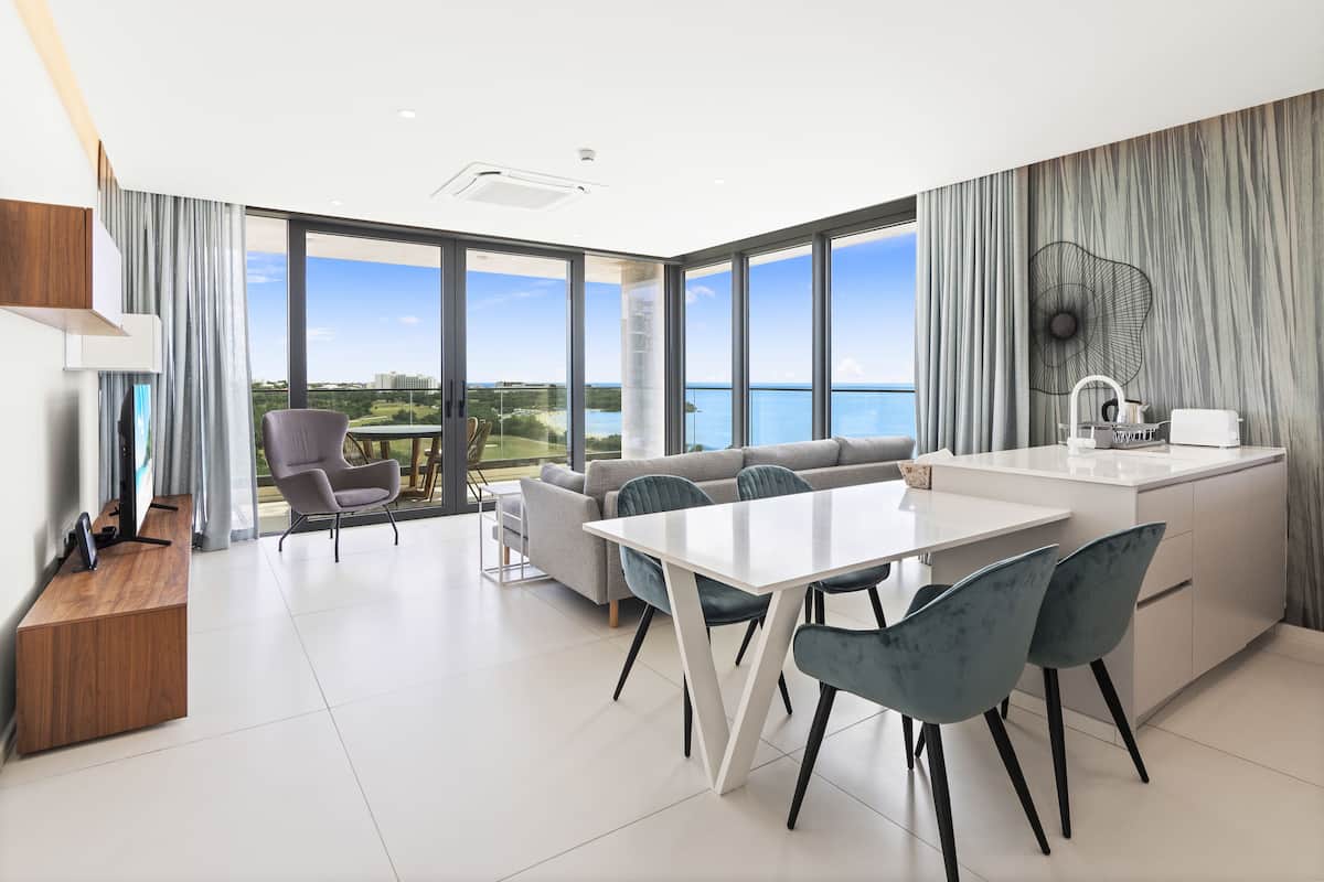 Un salon moderne avec un coin repas, de grandes fenêtres et une vue sur la mer.