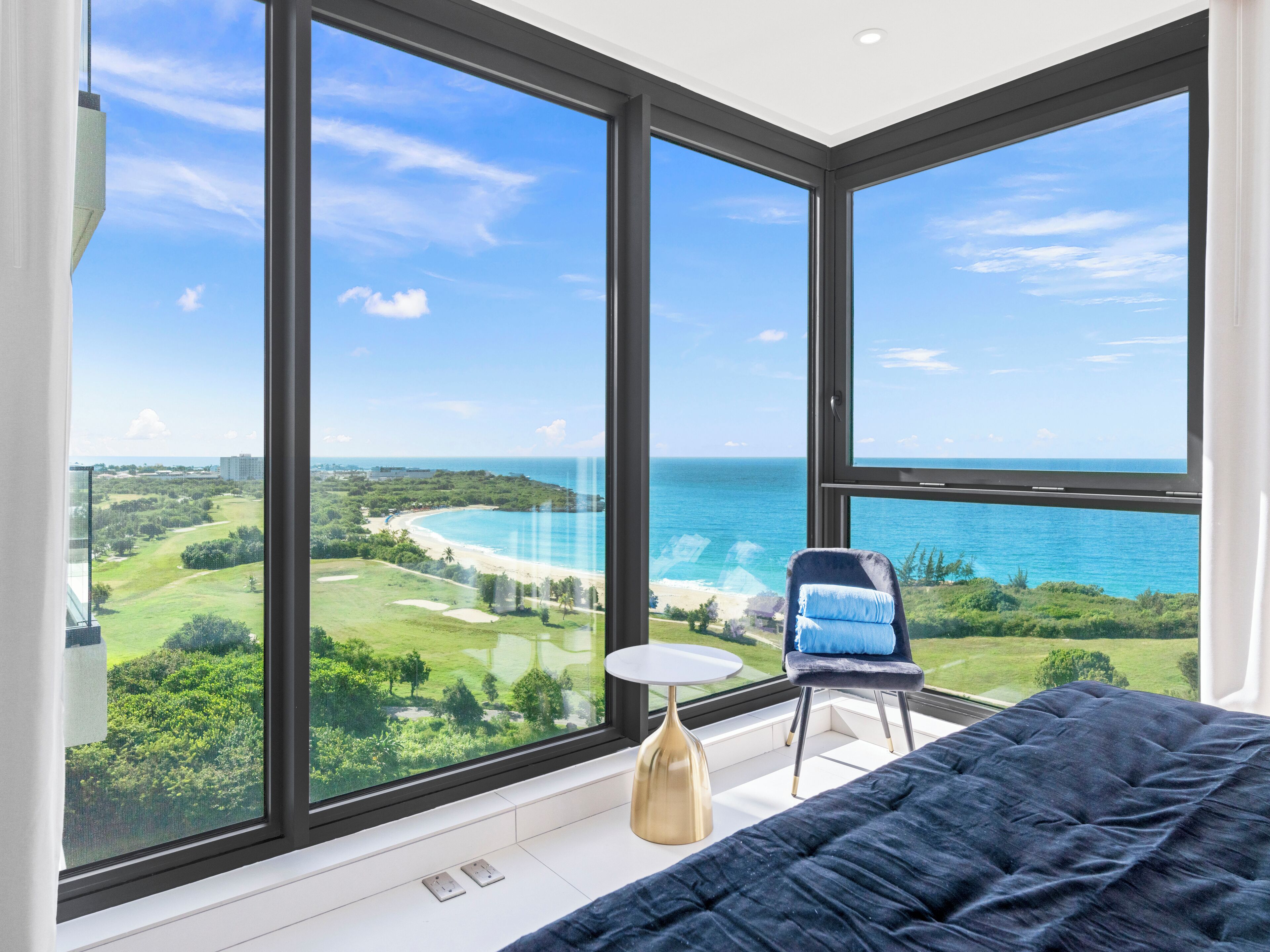 Une chambre avec une grande fenêtre donnant sur une plage et un terrain de golf.