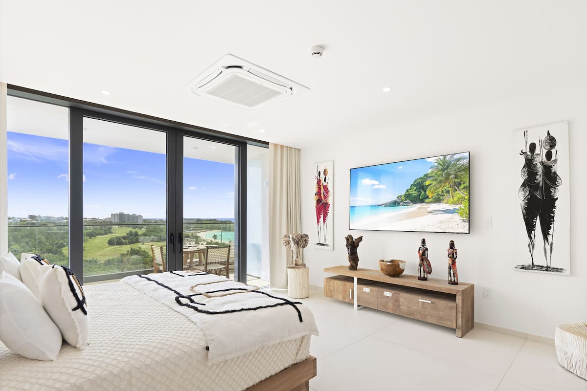Une chambre avec un grand lit, une télévision et des œuvres d’art accrochées au mur.