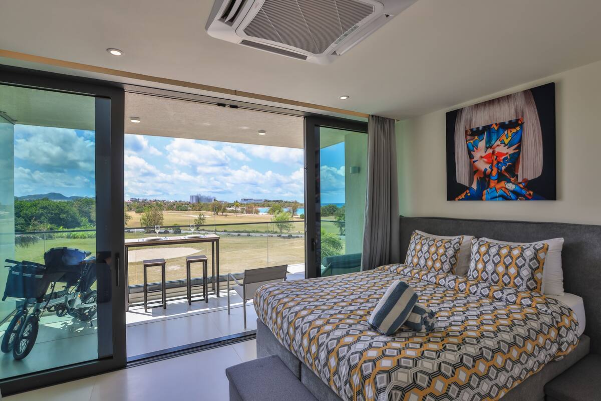 Une chambre moderne avec un grand lit, une vue sur un terrain de golf et une moto garée à l’extérieur.