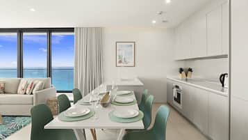 A modern dining area with a view of the ocean, a white kitchen with stainless steel appliances, and a cozy seating area with a view.
