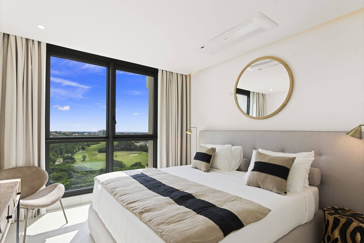 Une chambre d’hôtel moderne dotée d’un grand lit, d’un bureau et offrant une vue sur un terrain de golf.