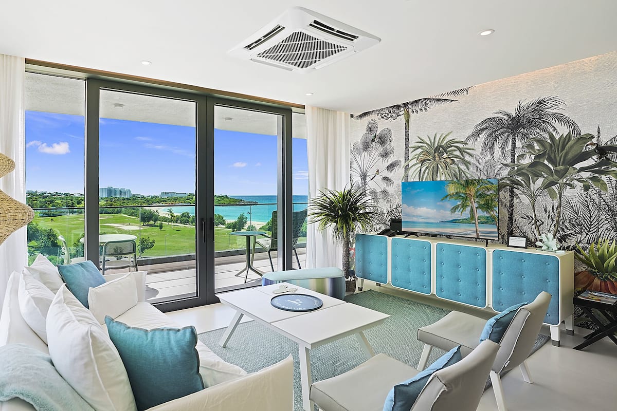 Un salon moderne doté d’une grande porte vitrée donnant sur un balcon avec vue sur l’océan.