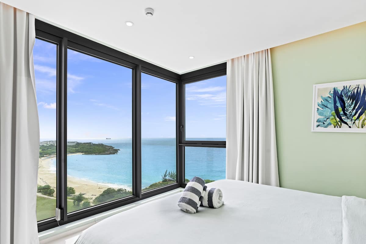 Une chambre dotée d’une grande fenêtre donnant sur la plage et l’océan.