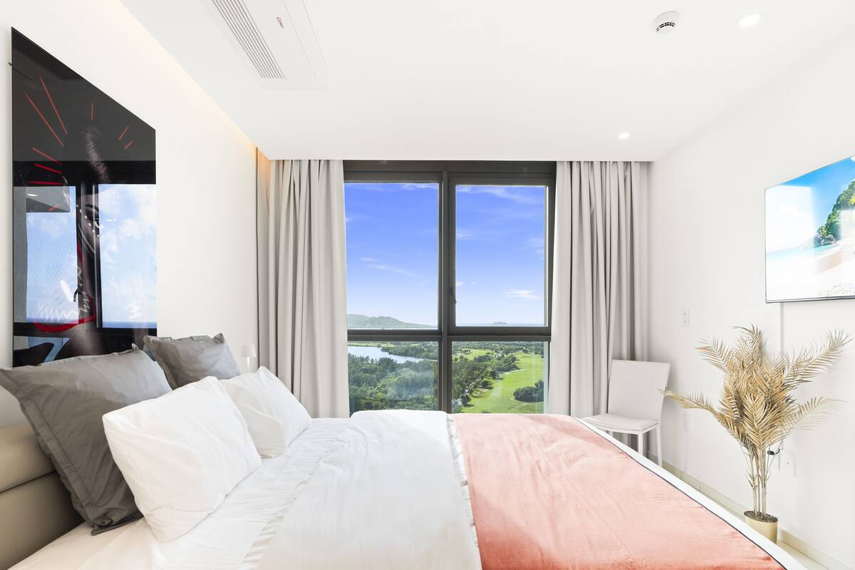 Une chambre d’hôtel avec un grand lit, une télévision, une vue sur un paysage et une plante en pot.