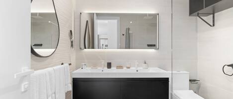 A modern bathroom with a large mirror, a vanity with a black sink, and a toilet.