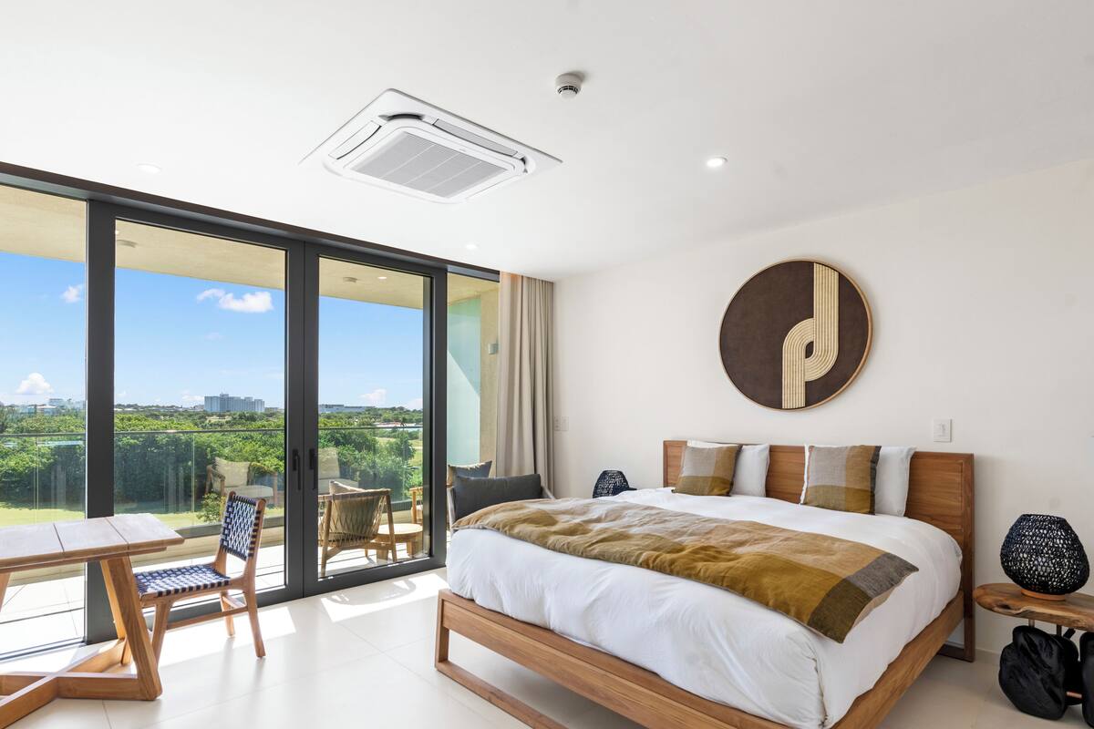 Une chambre d’hôtel moderne avec un grand lit, une table à manger et une chaise. Elle dispose d’un balcon avec vue sur la ville.