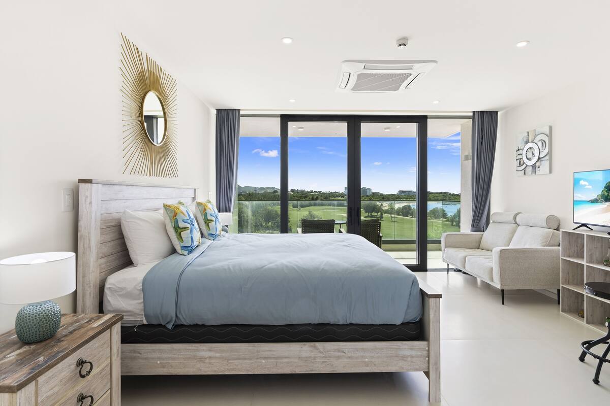 Une chambre moderne avec un grand lit, une télévision et une vue sur un terrain de golf.