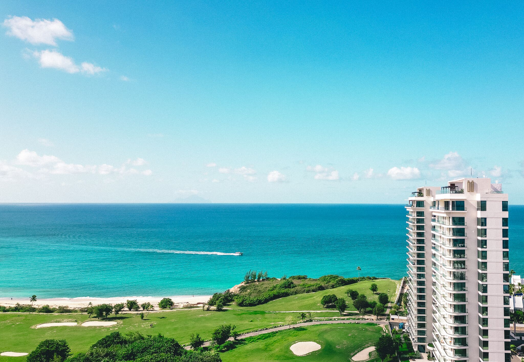 A high-rise hotel overlooking a beach with a clear view of the ocean.