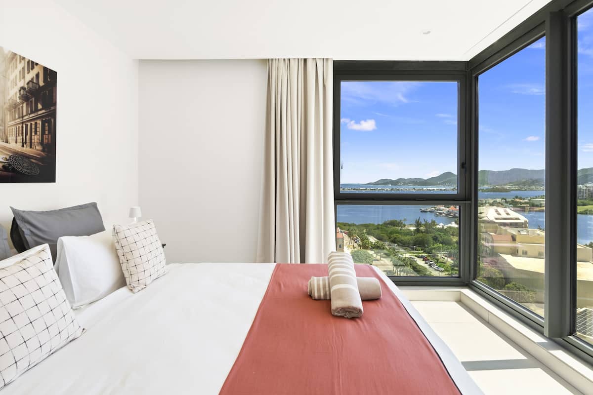 Une chambre d’hôtel avec un grand lit, une vue sur un paysage côtier et un tableau accroché au mur.