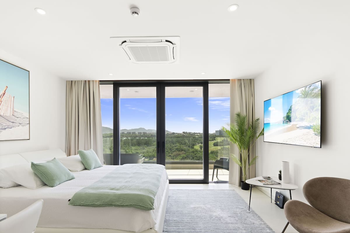 Une chambre d’hôtel moderne dotée d’un grand lit, d’un bureau, d’une chaise, d’une télévision et d’un balcon offrant une vue panoramique.