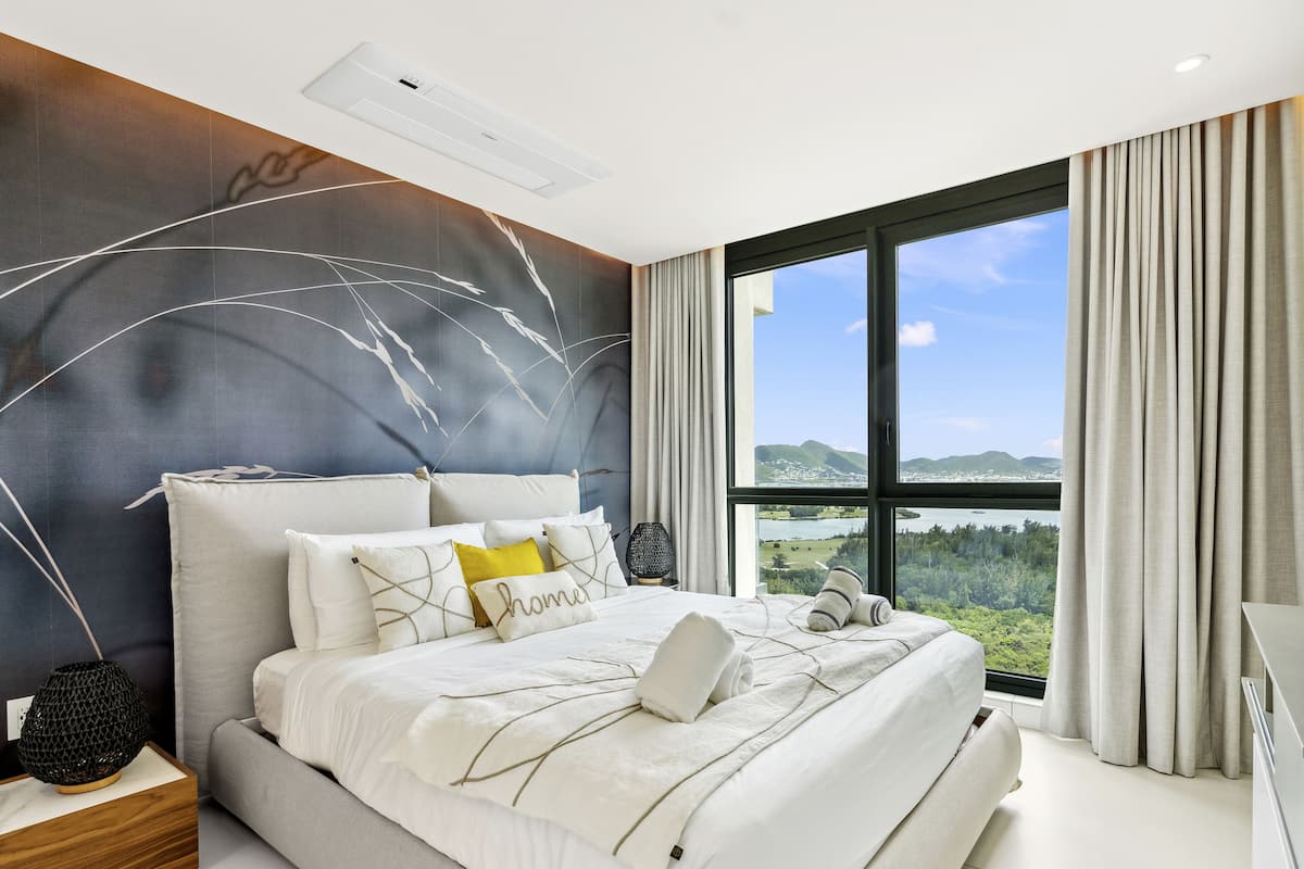 Une chambre moderne avec un grand lit, une vue sur l’extérieur et un climatiseur fixé au plafond.