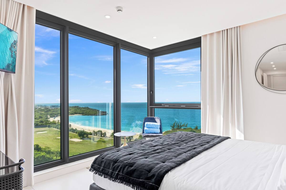 Une chambre dotée d’une grande fenêtre donnant sur l’océan et un terrain de golf.