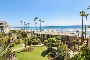 A resort with a rooftop pool, palm trees, and a view of the ocean.