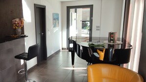 A modern kitchen with a black countertop, a vase of flowers, and a dining area with a black table and chairs.