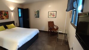 A bedroom with a bed, two wall-mounted light fixtures, a chair, and a television.