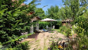 A patio area with a wooden deck, outdoor furniture, and a pergola with an umbrella.