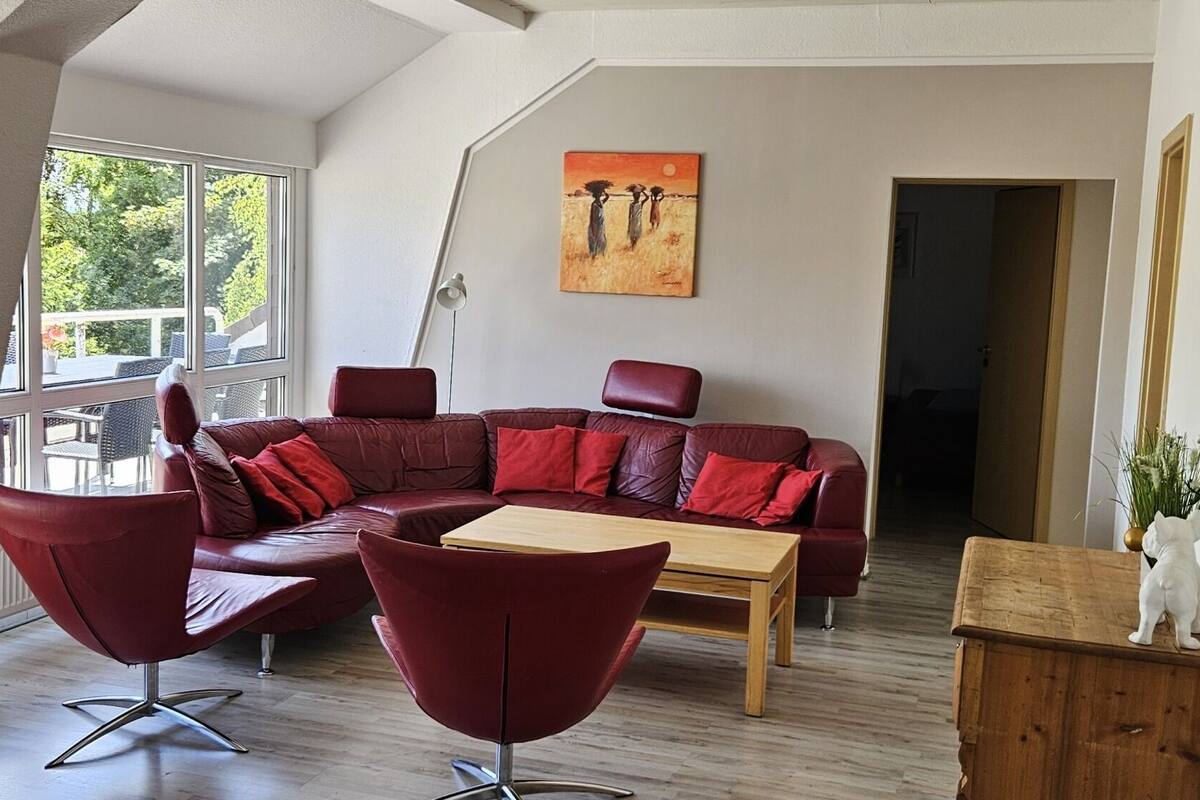 Ein modernes Wohnzimmer mit einem Ecksofa, zwei Sesseln, einem Holztisch und einem Gemälde an der Wand.