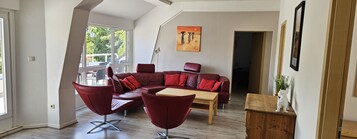 Una sala moderna con un sofá modular, dos sillones, una mesa de centro de madera y un cuadro en la pared.