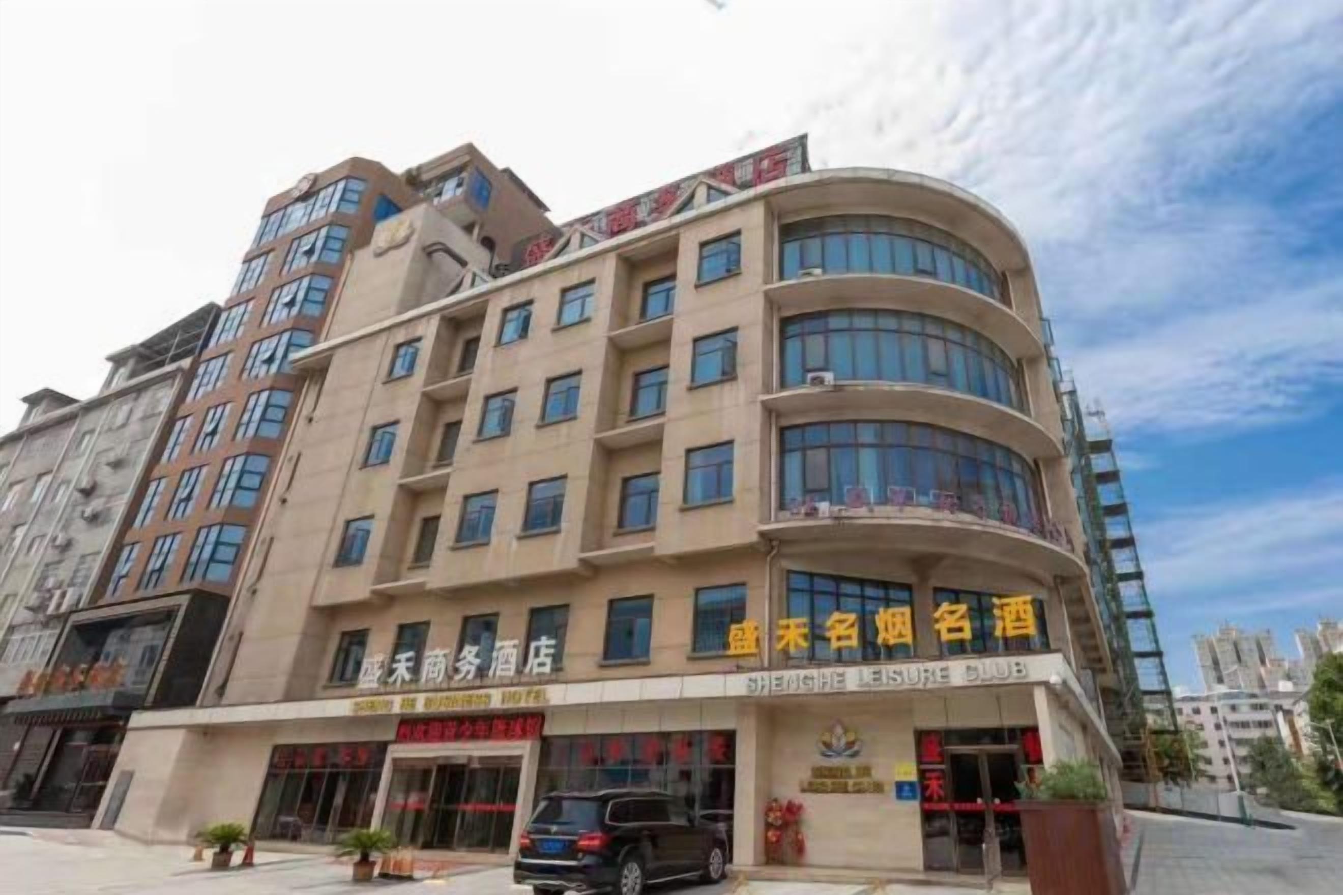A multi-story hotel with a curved facade, multiple balconies, and signage indicating a business hotel.
