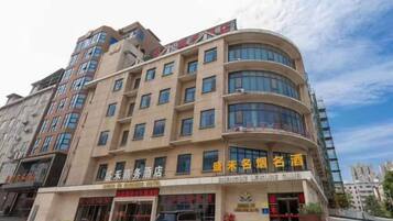 A multi-story hotel with a curved facade, multiple balconies, and signage indicating a business hotel.