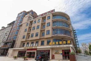 Un hôtel à plusieurs étages, doté d’une façade incurvée, de nombreux balcons et d’une enseigne indiquant qu’il s’agit d’un hôtel d’affaires.