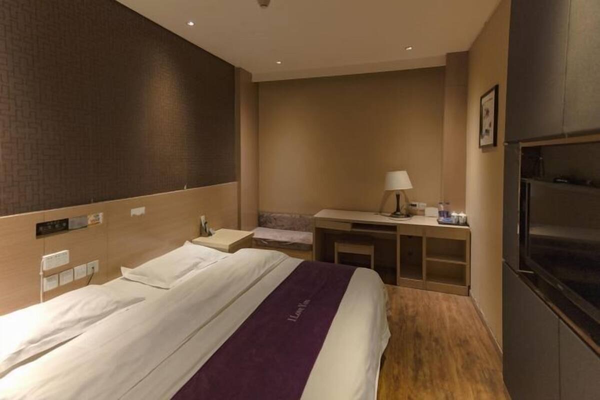 Une chambre d’hôtel avec un lit, un bureau, une chaise, une télévision et une lampe.