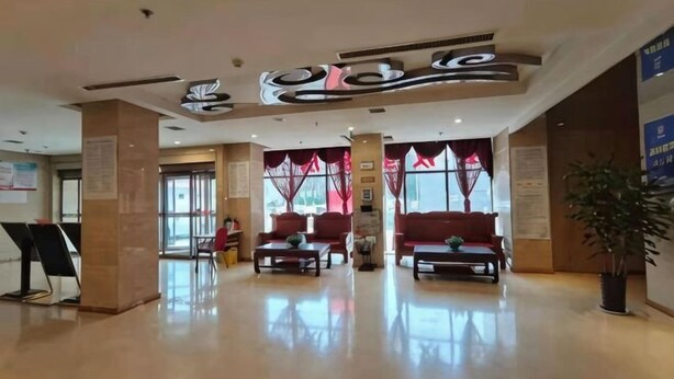 Un vestíbulo de hotel con mostrador de recepción, zona de estar y una planta grande.